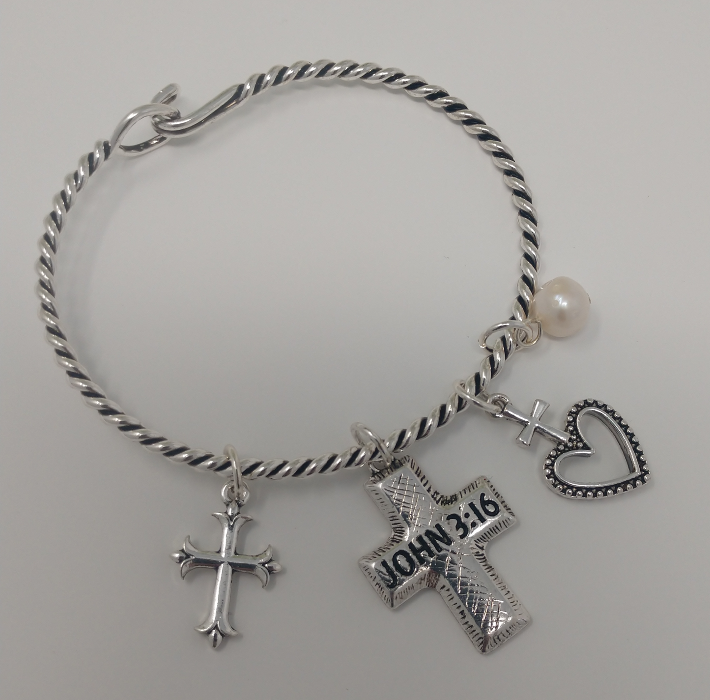 It is a twisted silver tone band with a 1.25" John 3:16 charm, a 1' cross and heart charm, a 1" cross charm and a .5" faux pear charm. It measures approximately 2"-2.25" in diameter. It is a beautiful and well designed hook closure.