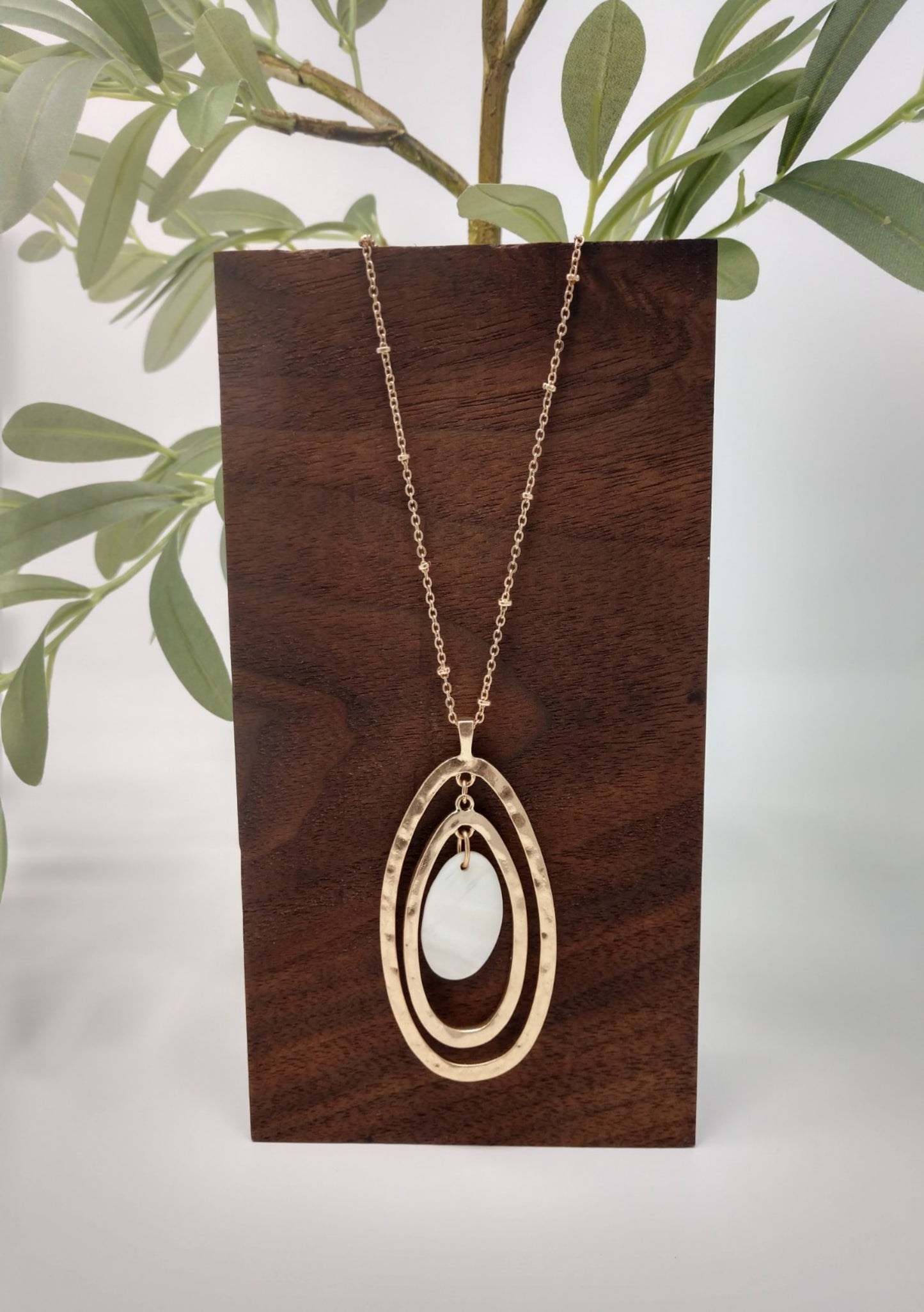 The necklace is made of a gold tone Saturn chain, two gold tone oval pendants with a mother of pearl oval in the center. It measures 18" long with a 3" extender and a lobster claw closure.