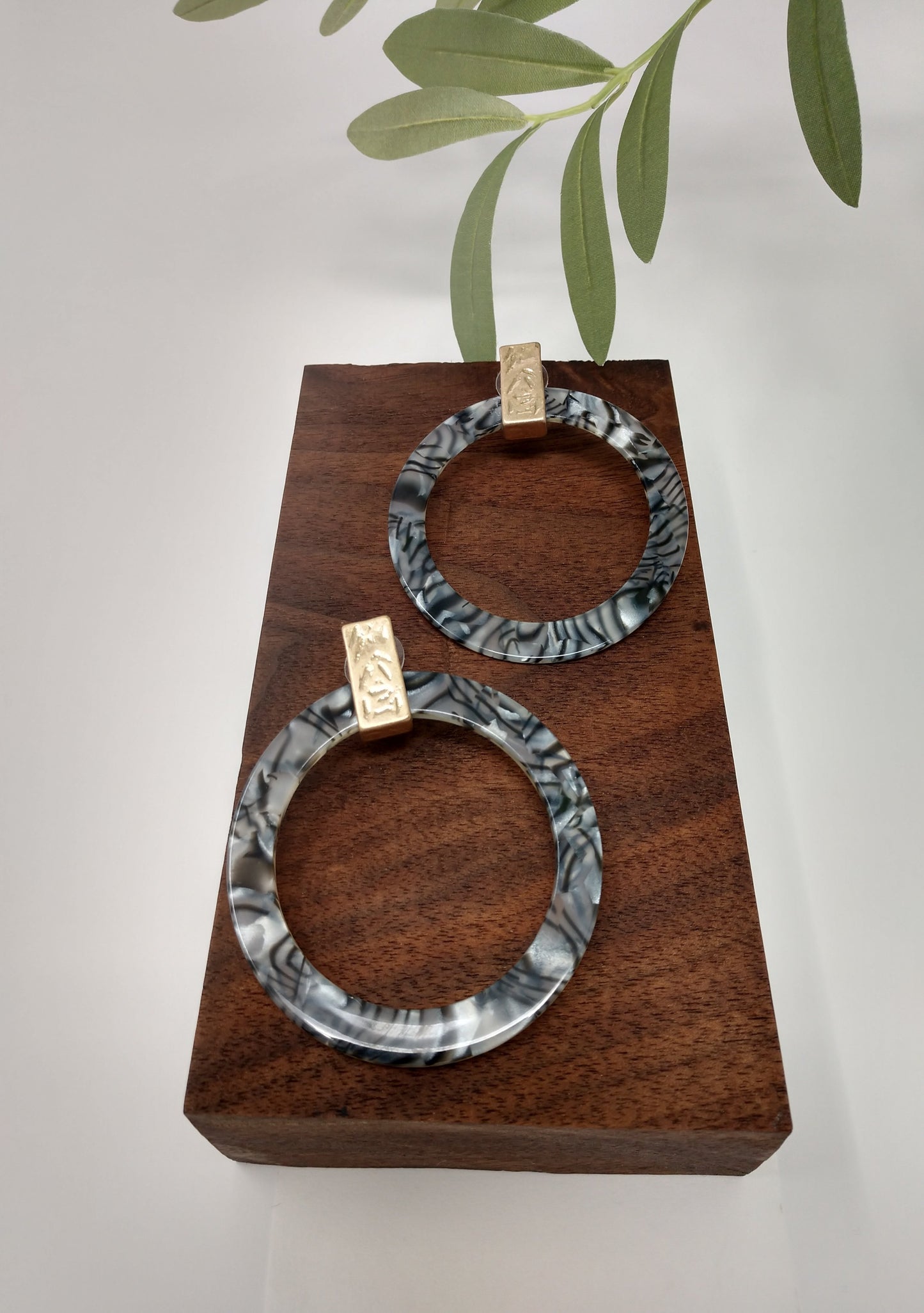 These hoops are a statement piece. They are a gray marbled print resin with a gold tone accent piece at top of earring. They are flat hoops and measure 2.75" and are a post style.