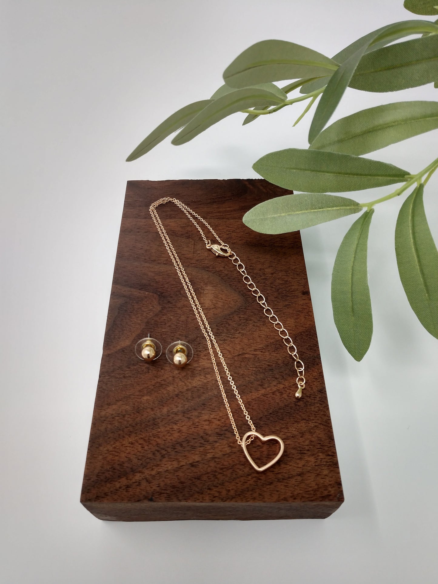 It is a 15" long worn gold tone chain with a 3" extender. The worn gold tone heart pendant measures approximately .5" and has a lobster claw closure. Plus, it comes with cute .25" post style earrings to match.
