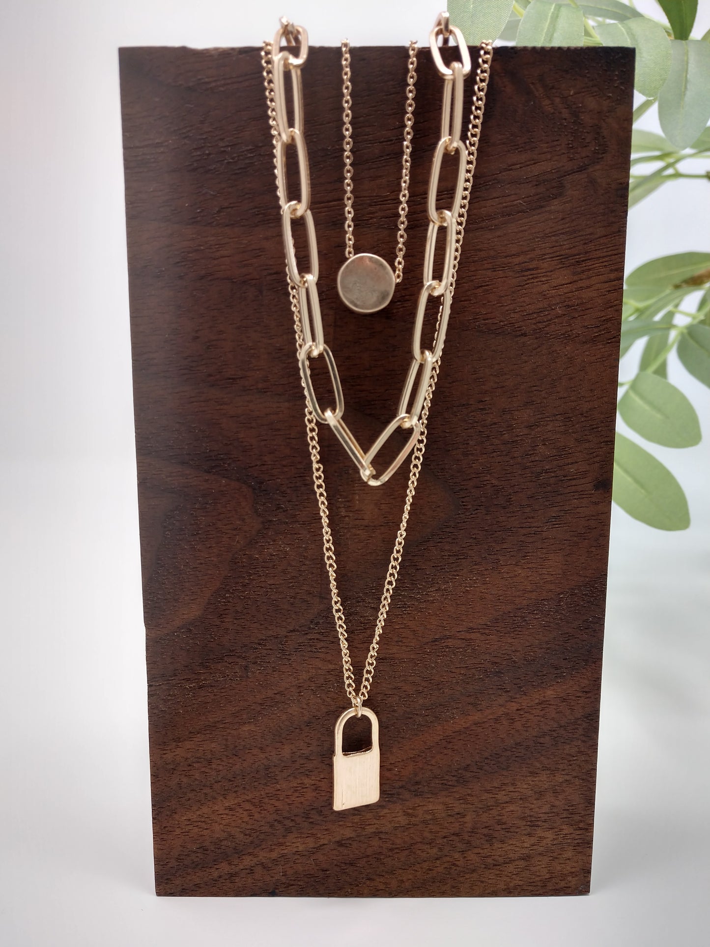 It would make a great gift for the hard to buy for teen or for your trendy self! It is a 16" long chain with a 3" extender and a disc pendant, a 20" long middle linked chain, and a 24" bottom chain with padlock. The worn gold tone gives it a unique look and the padlock and disc pendants measure up to .75". Lobster claw closure.