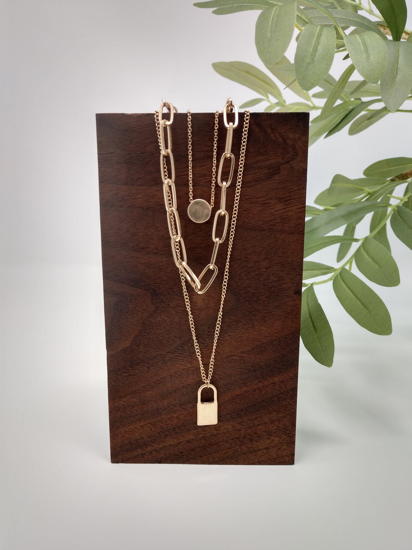 It would make a great gift for the hard to buy for teen or for your trendy self! It is a 16" long chain with a 3" extender and a disc pendant, a 20" long middle linked chain, and a 24" bottom chain with padlock. The worn gold tone gives it a unique look and the padlock and disc pendants measure up to .75". Lobster claw closure.