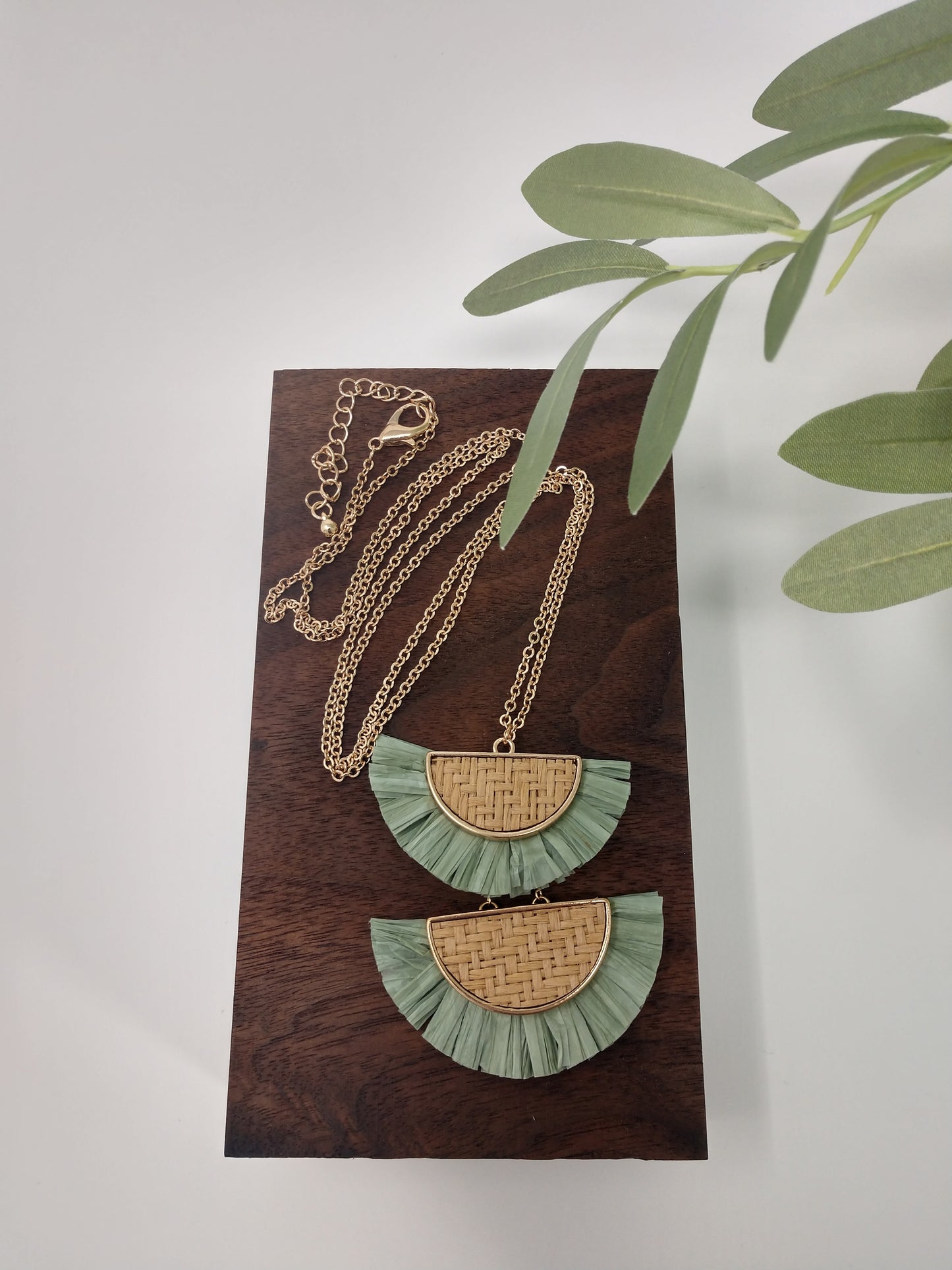 It is a 30" long gold tone necklace with a 3" extender and lobster claw closure. It is made with rattan, and raffia material. The pendant measures 2.5" and is so delicate feeling. Plus, it comes with the most perfect set of earrings. They are .75" fish hook style with a .25 drop. Fashion jewelry is a great way to add affordable fun, colorful, trendy pieces to your collection.