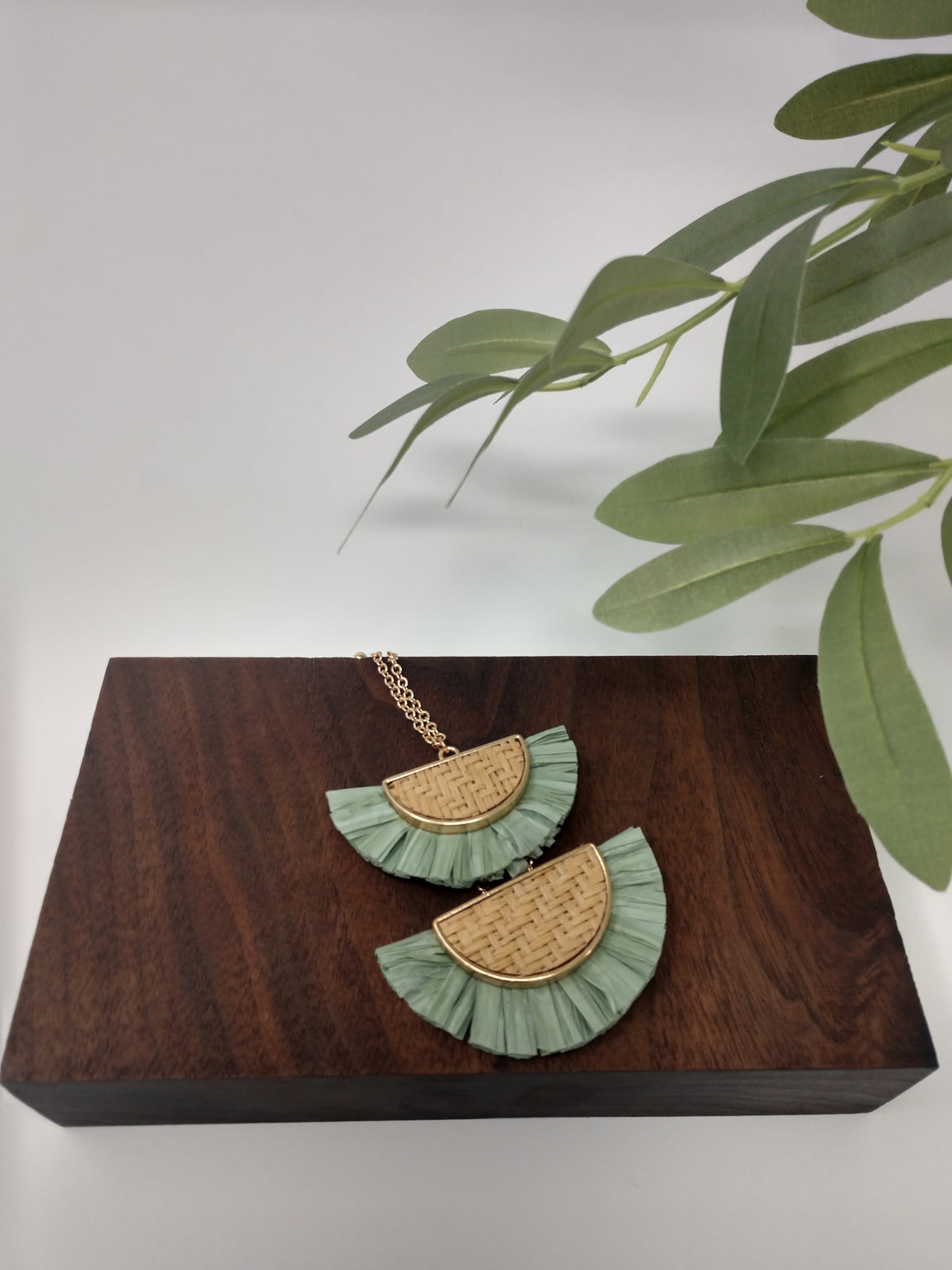 It is a 30" long gold tone necklace with a 3" extender and lobster claw closure. It is made with rattan, and raffia material. The pendant measures 2.5" and is so delicate feeling. Plus, it comes with the most perfect set of earrings. They are .75" fish hook style with a .25 drop.Fashion jewelry is a great way to add affordable fun, colorful, trendy pieces to your collection.