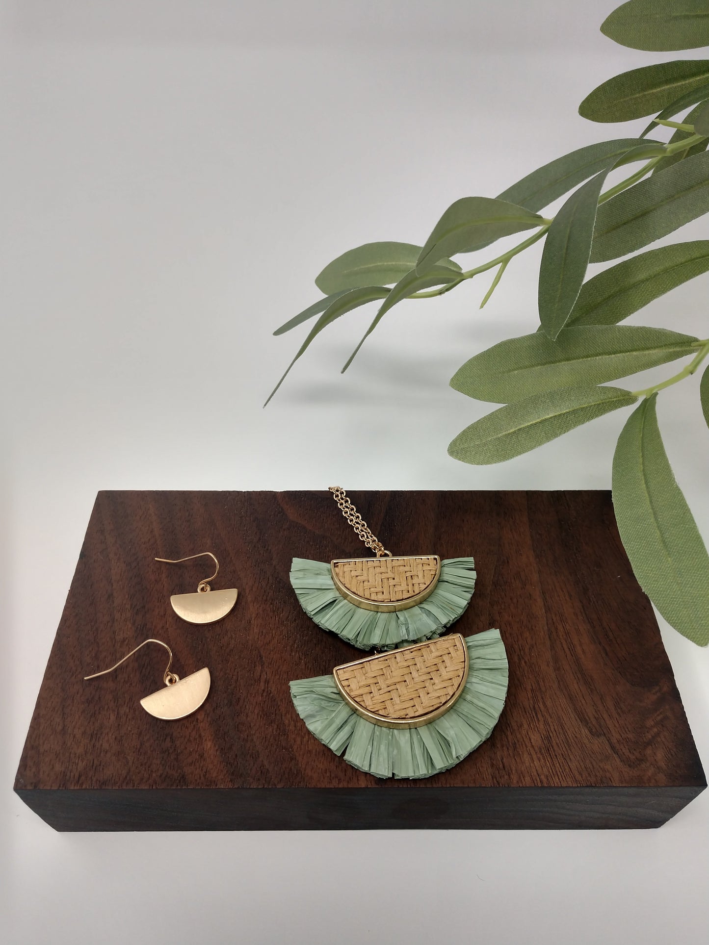 It is a 30" long gold tone necklace with a 3" extender and lobster claw closure. It is made with rattan, and raffia material. The pendant measures 2.5" and is so delicate feeling. Plus, it comes with the most perfect set of earrings. They are .75" fish hook style with a .25 drop. Fashion jewelry is a great way to add affordable fun, colorful, trendy pieces to your collection.