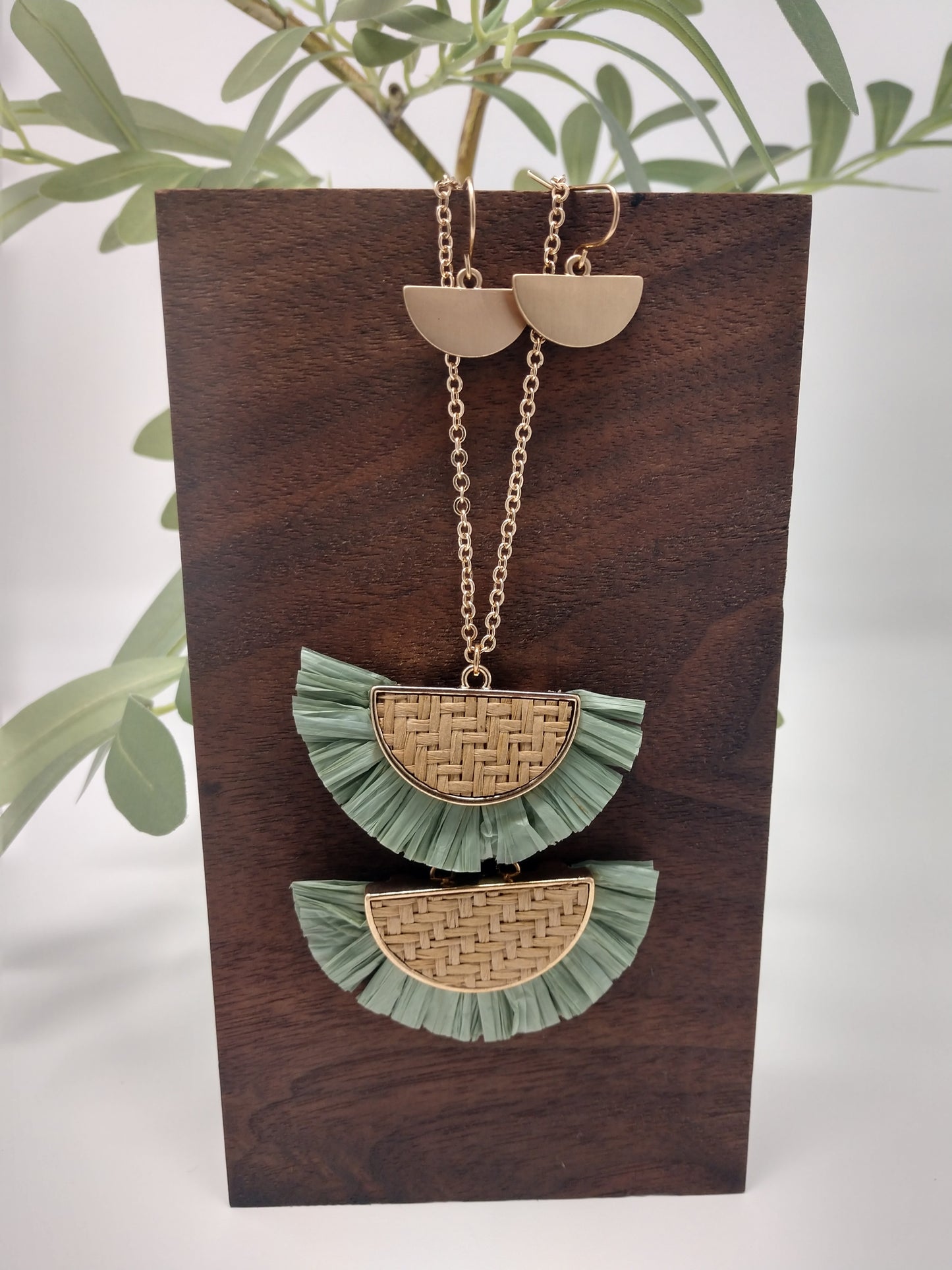 It is a 30" long gold tone necklace with a 3" extender and lobster claw closure. It is made with rattan, and raffia material. The pendant measures 2.5" and is so delicate feeling. Plus, it comes with the most perfect set of earrings. They are .75" fish hook style with a .25 drop. Fashion jewelry is a great way to add affordable fun, colorful, trendy pieces to your collection.
