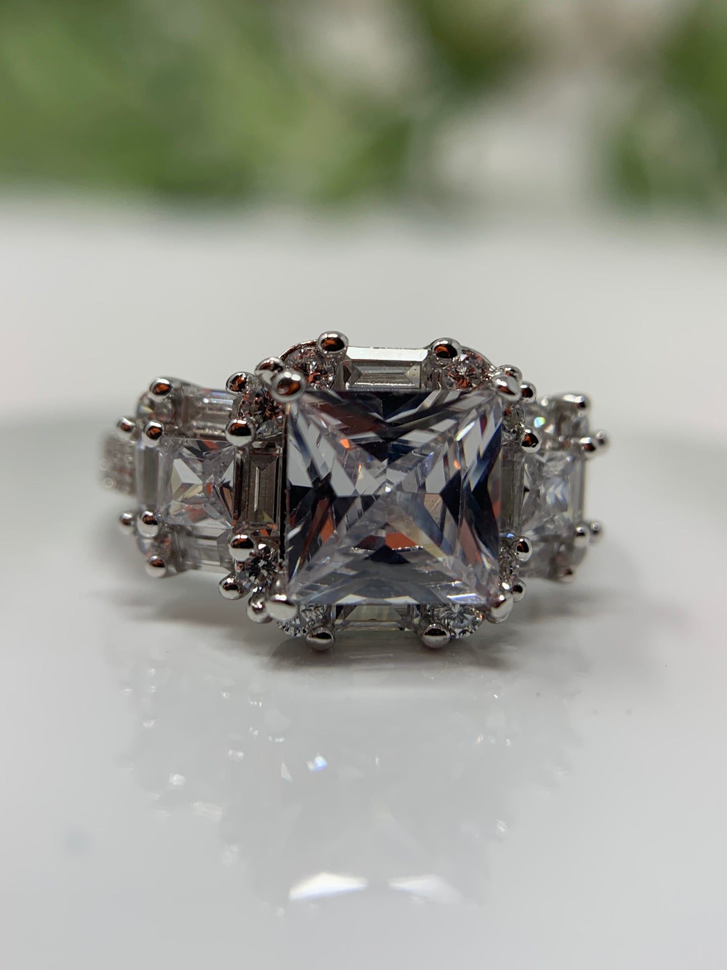 The ring has a mix of cubic zirconia (41 to be exact) in a variety of cuts. This stunner is a sterling silver ring is plated in rhodium to prevent tarnishing. The center stone is 1.28 carat princess cut cubic zirconia. The ring is finished off with 40 other stones, emerald and round cut.