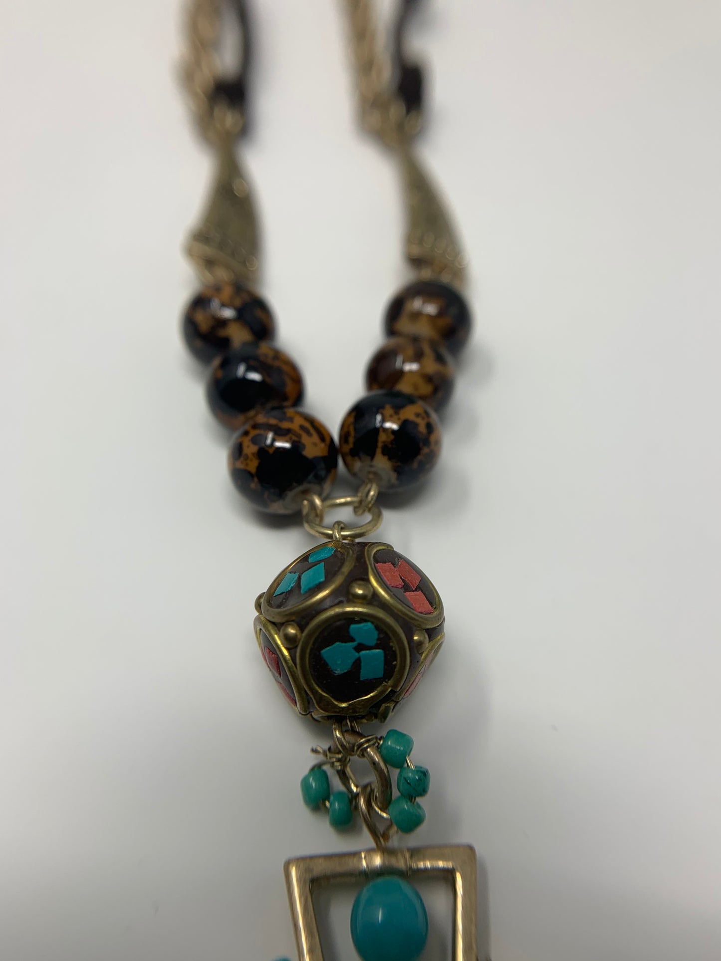 The necklace measures 14.6" with a 2" extender and matching arrowhead earrings. Gold tone chain with brown rope connects to two engraved goldtone charms that connect to faux tiger eye beads and a unique bead with bright teal and read accents. The arrow head pendant is goldtone with turquoise colored beads and has a silver tone arrow with turquoise and red colored stones. Earrings match the pendant except they have leather cord instead of silver tone arrow. Fashion jewelry, affordable jewelry
