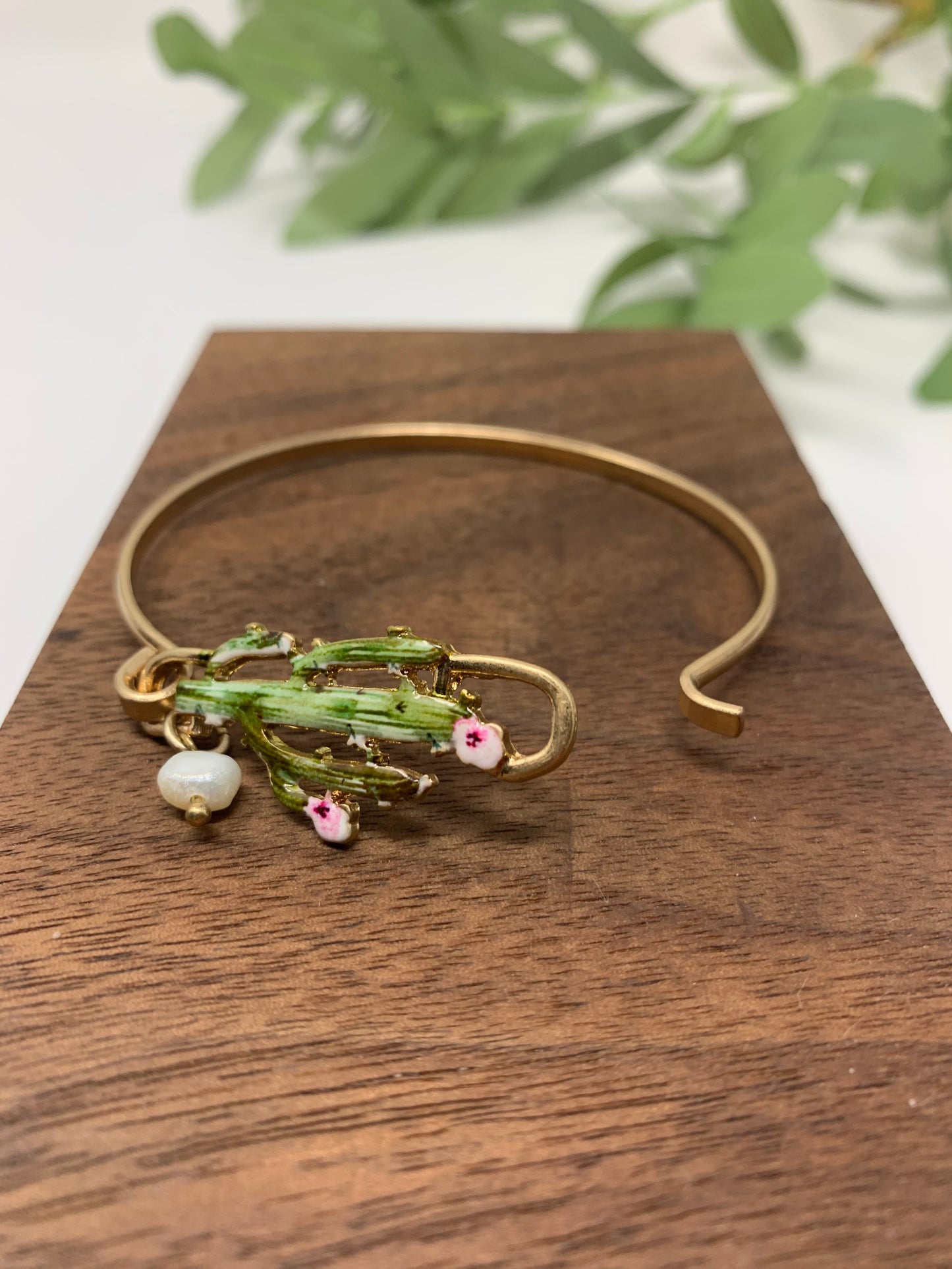 Gold tone bracelet with cactus that is colored perfectly. Wire bracelet closes with a hood closure and a faux pearl charm to add a touch of fancy.