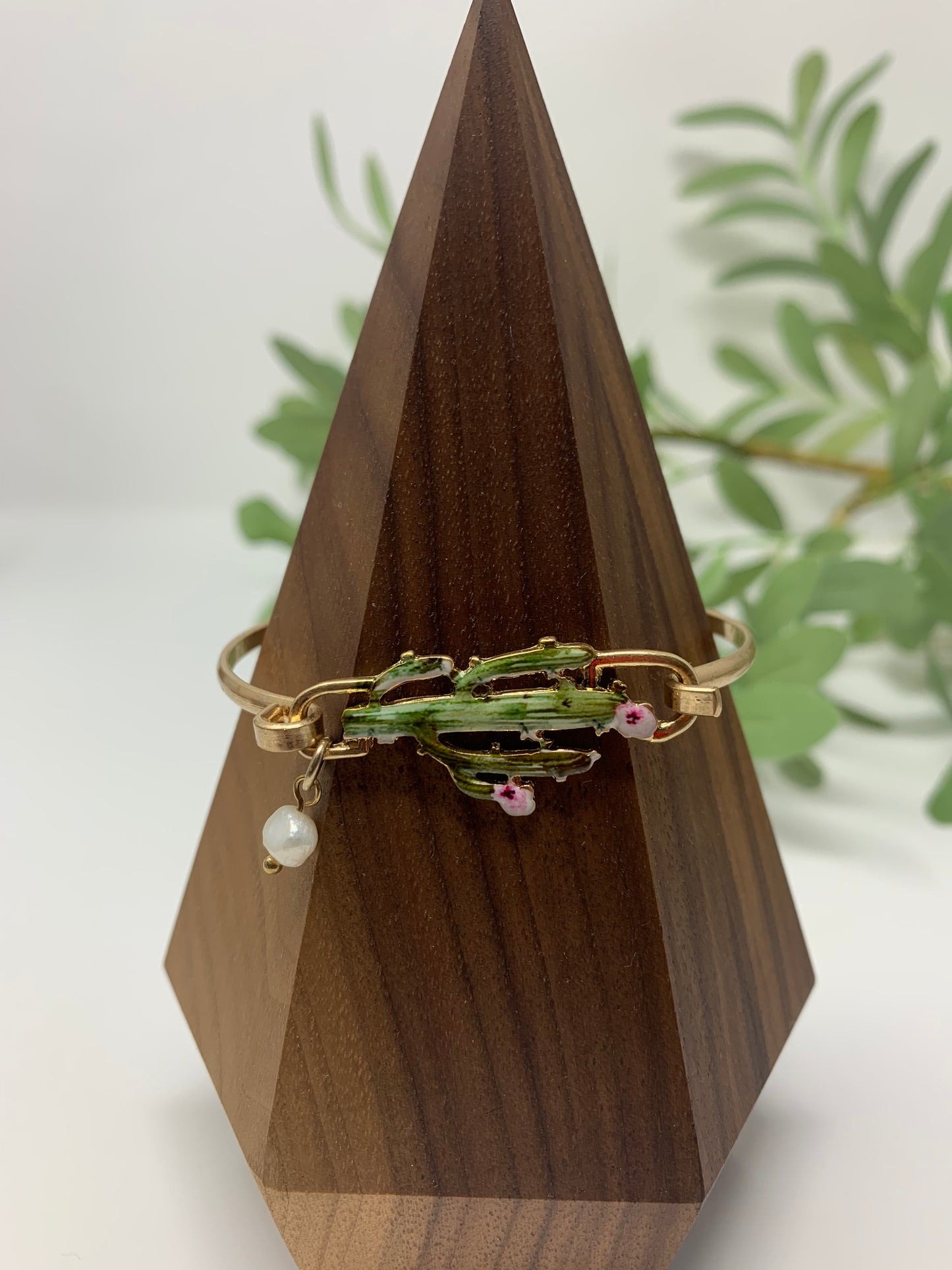 Gold tone bracelet with cactus that is colored perfectly. Wire bracelet closes with a hood closure and a faux pearl charm to add a touch of fancy.