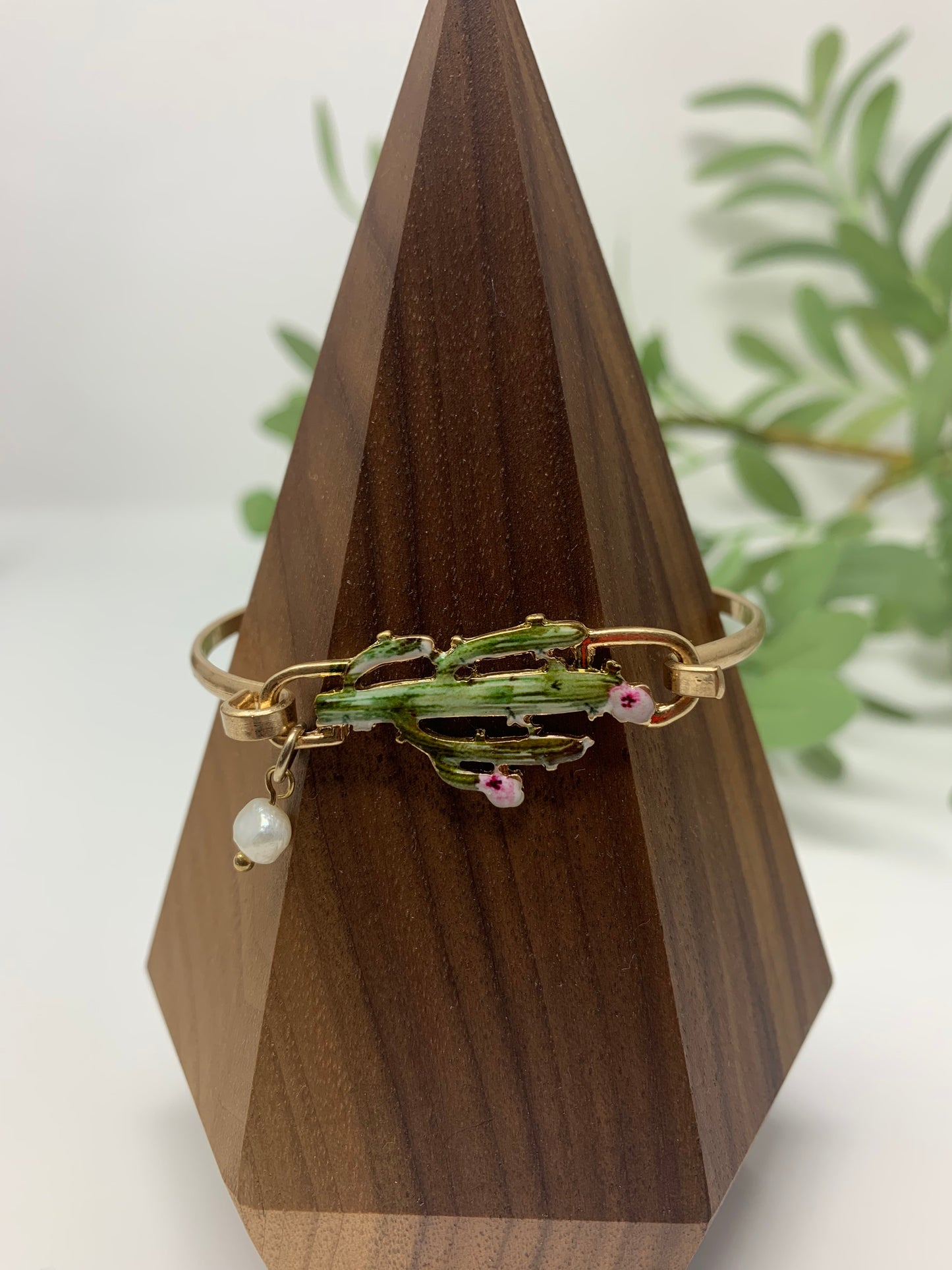 Gold tone bracelet with cactus that is colored perfectly. Wire bracelet closes with a hood closure and a faux pearl charm to add a touch of fancy.