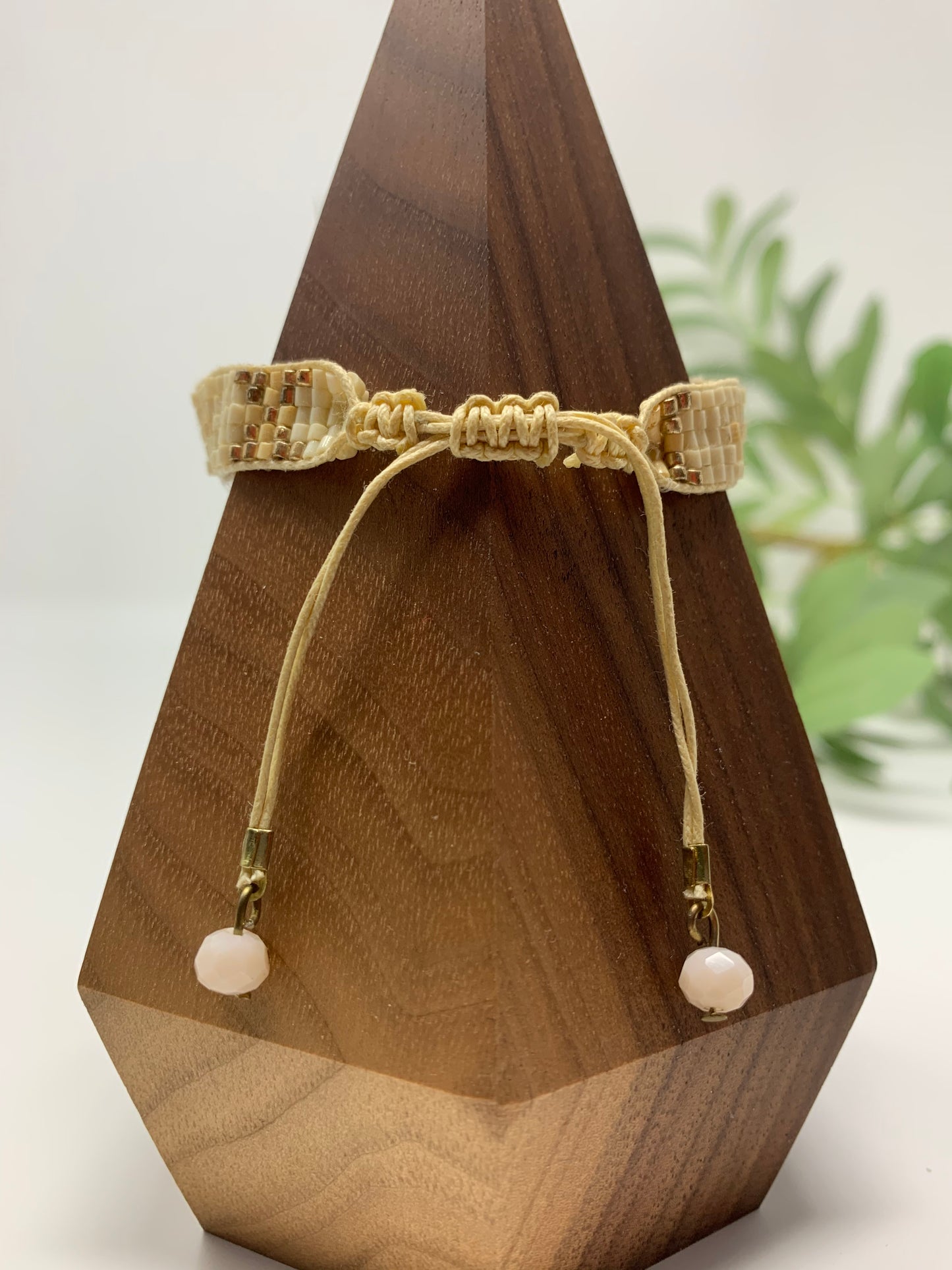 adjustable closure adorned with faceted beads on end. The beautiful seed beads in white, ivory and gold compliment the round smooth stone like charm. Set of three bracelets with adjustable cords and faceted ivory/light pink tones adorning the ends.