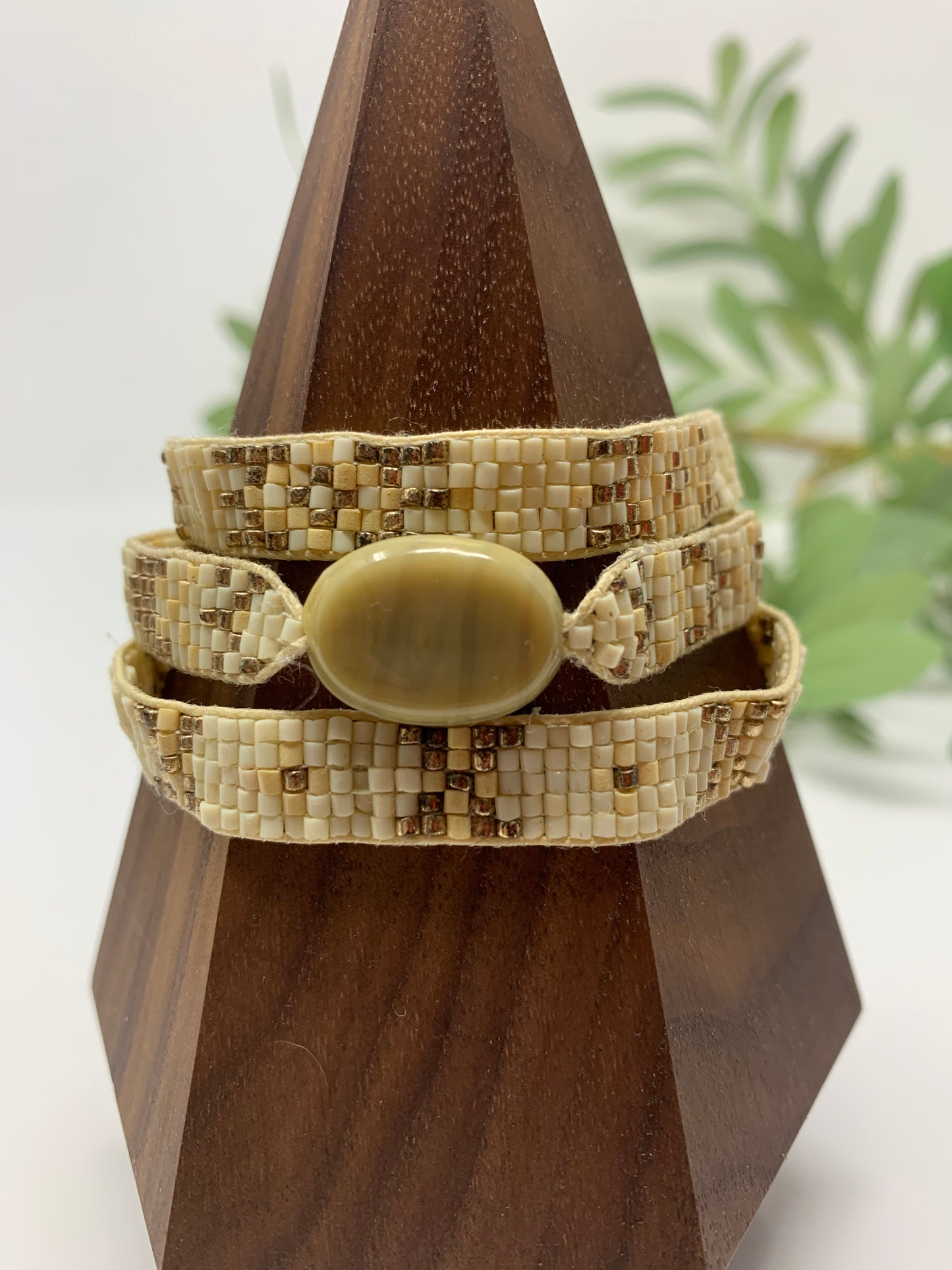 Set of three bracelets The beautiful seed beads in white, ivory and gold compliment the round smooth stone like charm. Set of three bracelets with adjustable cords and faceted ivory/light pink tones adorning the ends.
