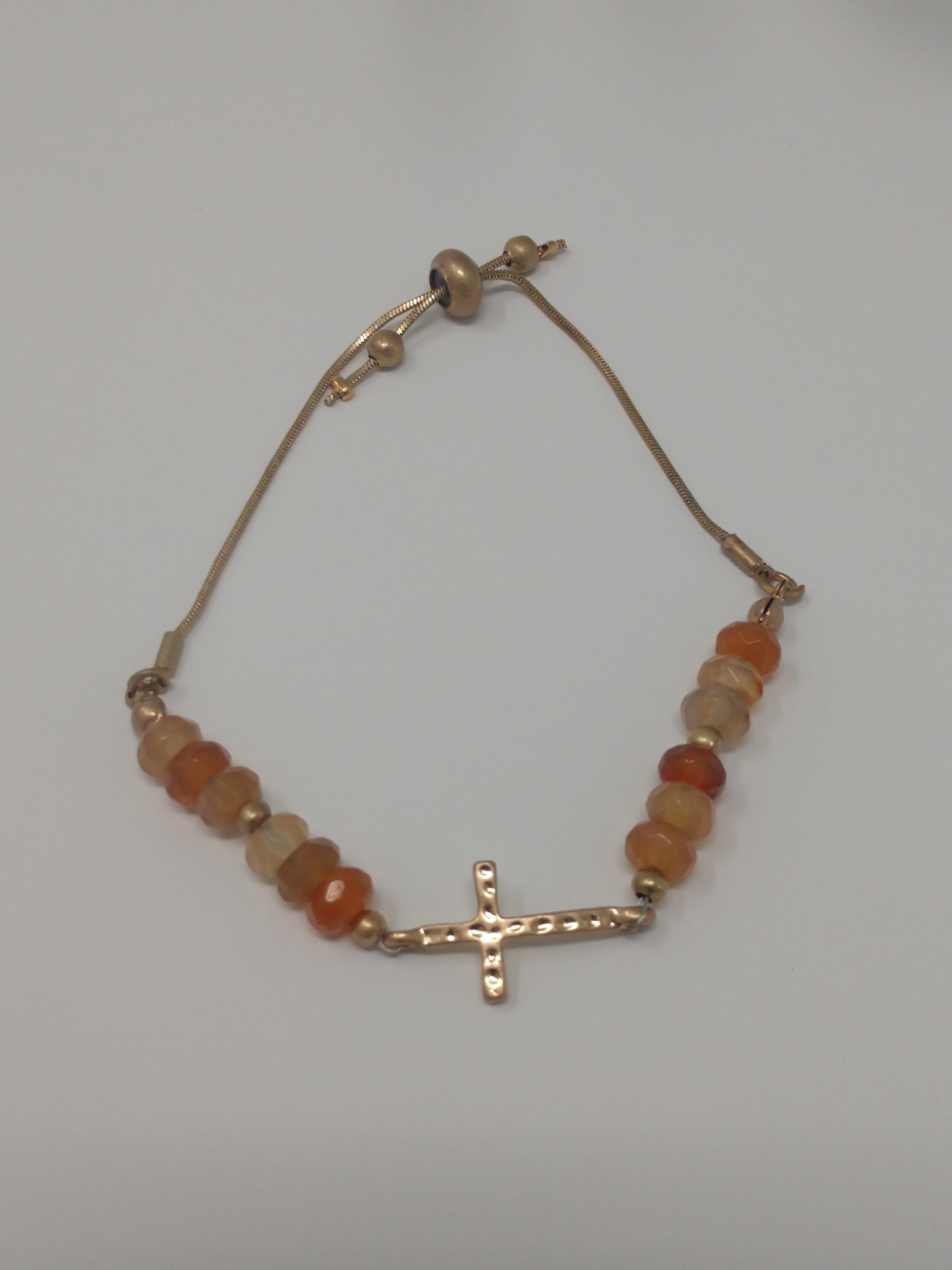 The gold tone cross and peach beads pair so well. It is a unique adjustable pull chain bracelet so there is no clasp closure.