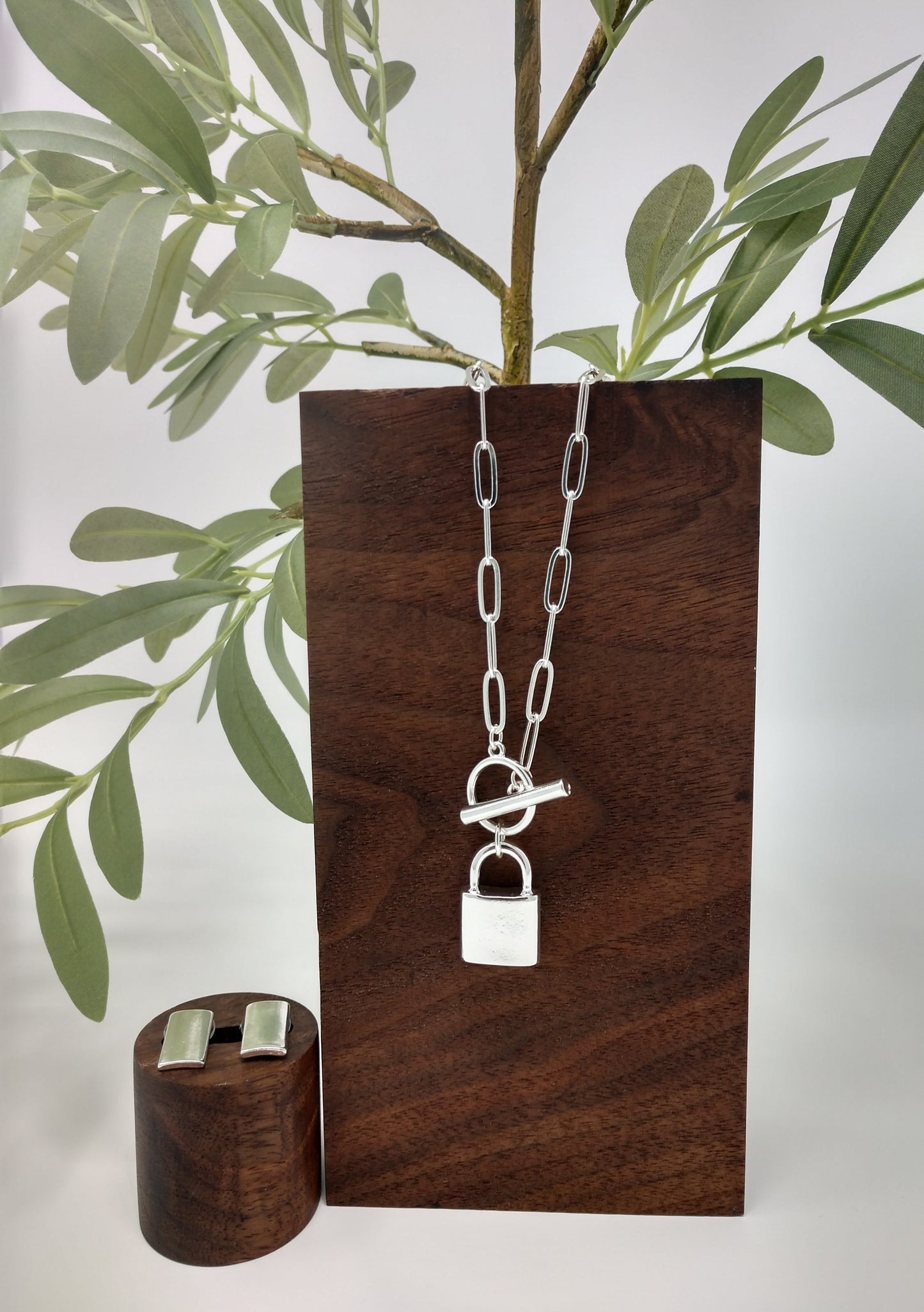 Padlock jewelry is so trendy right now and this silver tone necklace set is perfect! Can be layered for a unique look or worn alone. Great gift ideas for teens or for yourself! This linked chain necklace measures approximately 15.5", with a padlock pendant measuring up to 1" with a toggle closure. Post back rectangle earrings complete the look!