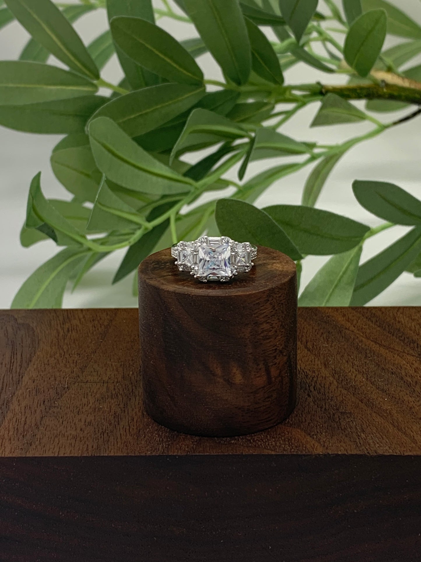 The ring has a mix of cubic zirconia (41 to be exact) in a variety of cuts. This stunner is a sterling silver ring is plated in rhodium to prevent tarnishing. The center stone is 1.28 carat princess cut cubic zirconia. The ring is finished off with 40 other stones, emerald and round cut.