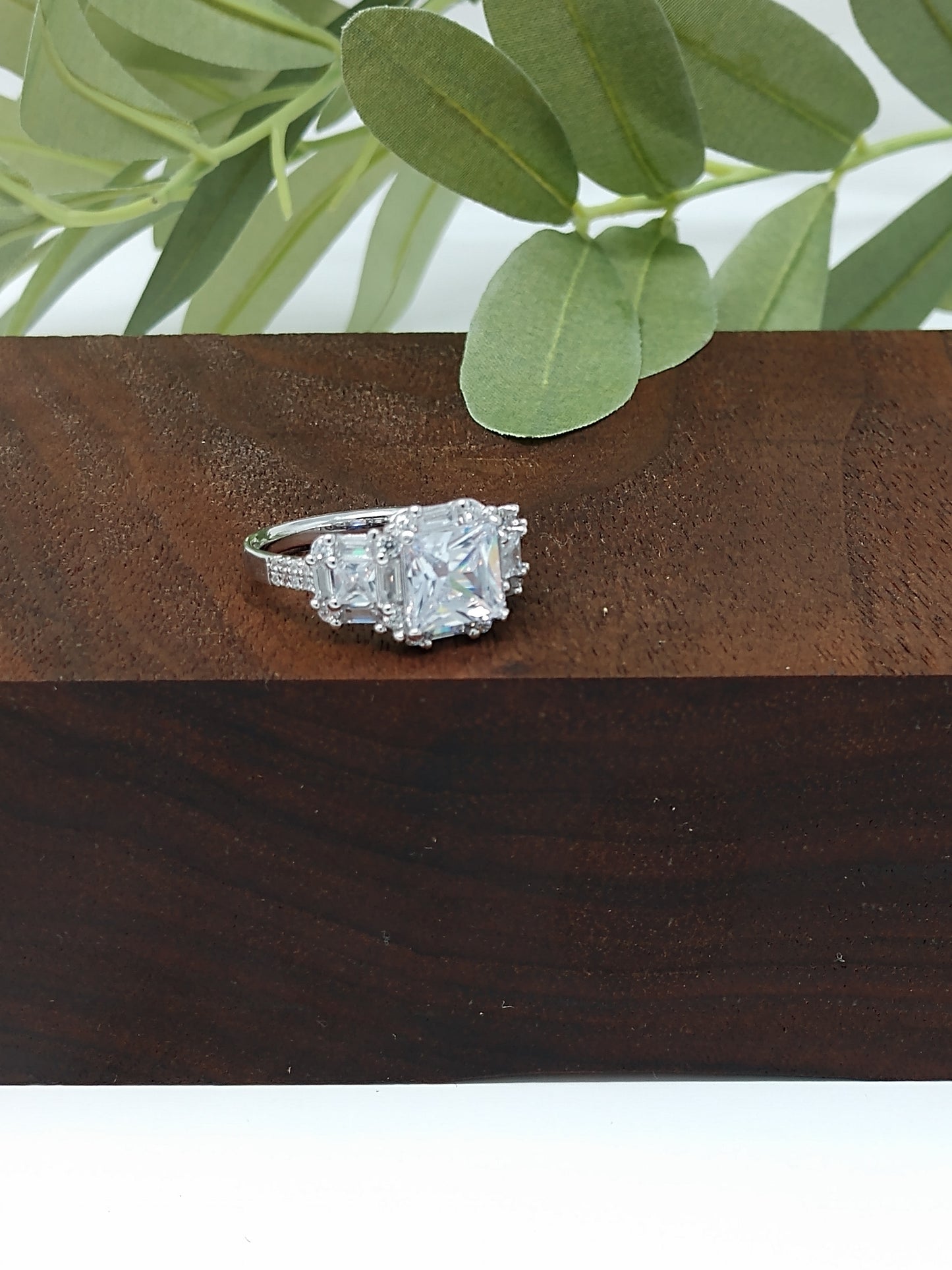 The ring has a mix of cubic zirconia (41 to be exact) in a variety of cuts. This stunner is a sterling silver ring is plated in rhodium to prevent tarnishing. The center stone is 1.28 carat princess cut cubic zirconia. The ring is finished off with 40 other stones, emerald and round cut.