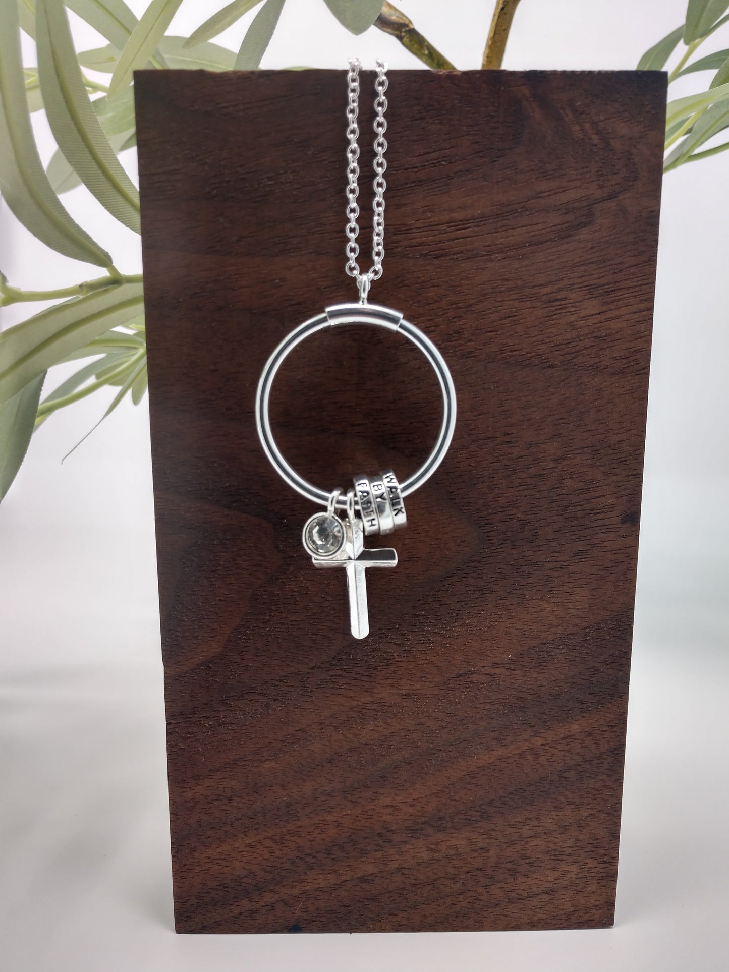 This is an antique silver tone necklace that is 18" with a 3" extender with a lobster claw closure. It is beautifully finished with a 2.5" ring pendant with sliding rings each engraved, cross charm, and framed rhinestone charm.