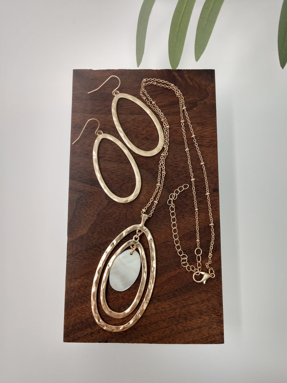 Necklace & Earring Set The necklace is made of a gold tone Saturn chain, two gold tone oval pendants with a mother of pearl oval in the center. It measures 18" long with a 3" extender and a lobster claw closure. The earrings are a 1.5" fish hook style earring with a 1.25" drop. They are gold tone ovals to match the necklace.
