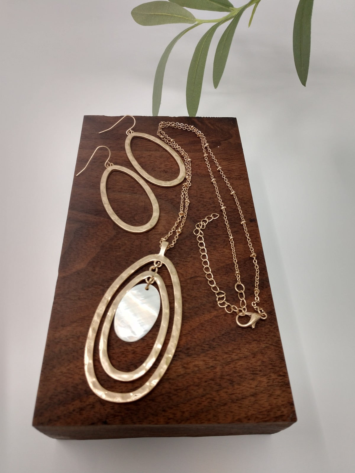 The necklace is made of a gold tone Saturn chain, two gold tone oval pendants with a mother of pearl oval in the center. It measures 18" long with a 3" extender and a lobster claw closure. The earrings are a 1.5" fish hook style earring with a 1.25" drop. They are gold tone ovals to match the necklace.