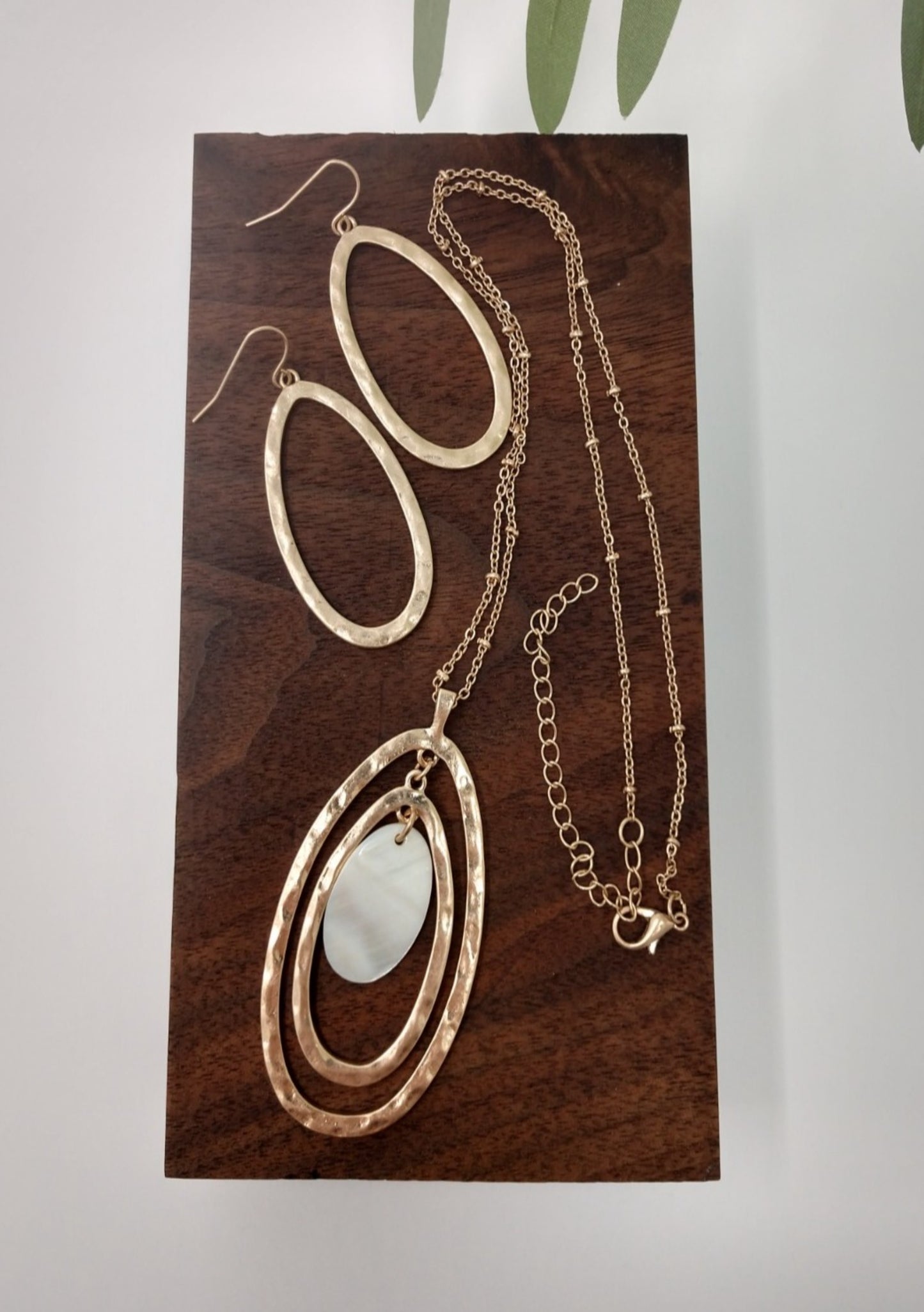 The necklace is made of a gold tone Saturn chain, two gold tone oval pendants with a mother of pearl oval in the center. It measures 18" long with a 3" extender and a lobster claw closure. The earrings are a 1.5" fish hook style earring with a 1.25" drop. They are gold tone ovals to match the necklace.