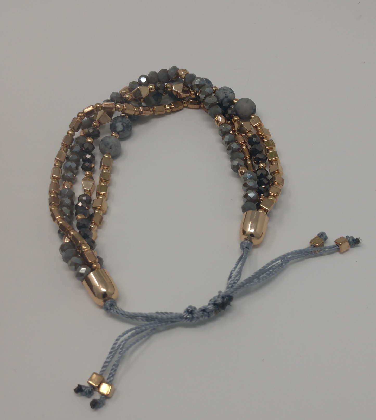 This bracelet is so perfect. It has four strands of gray Jasper and gold tone beads. The mix of faceted and smooth beads offers a neat mix especially being paired with the round, cube, rectangle and double pyramid beads. This is a pull adjustable cord bracelet so there is no clasp closure.