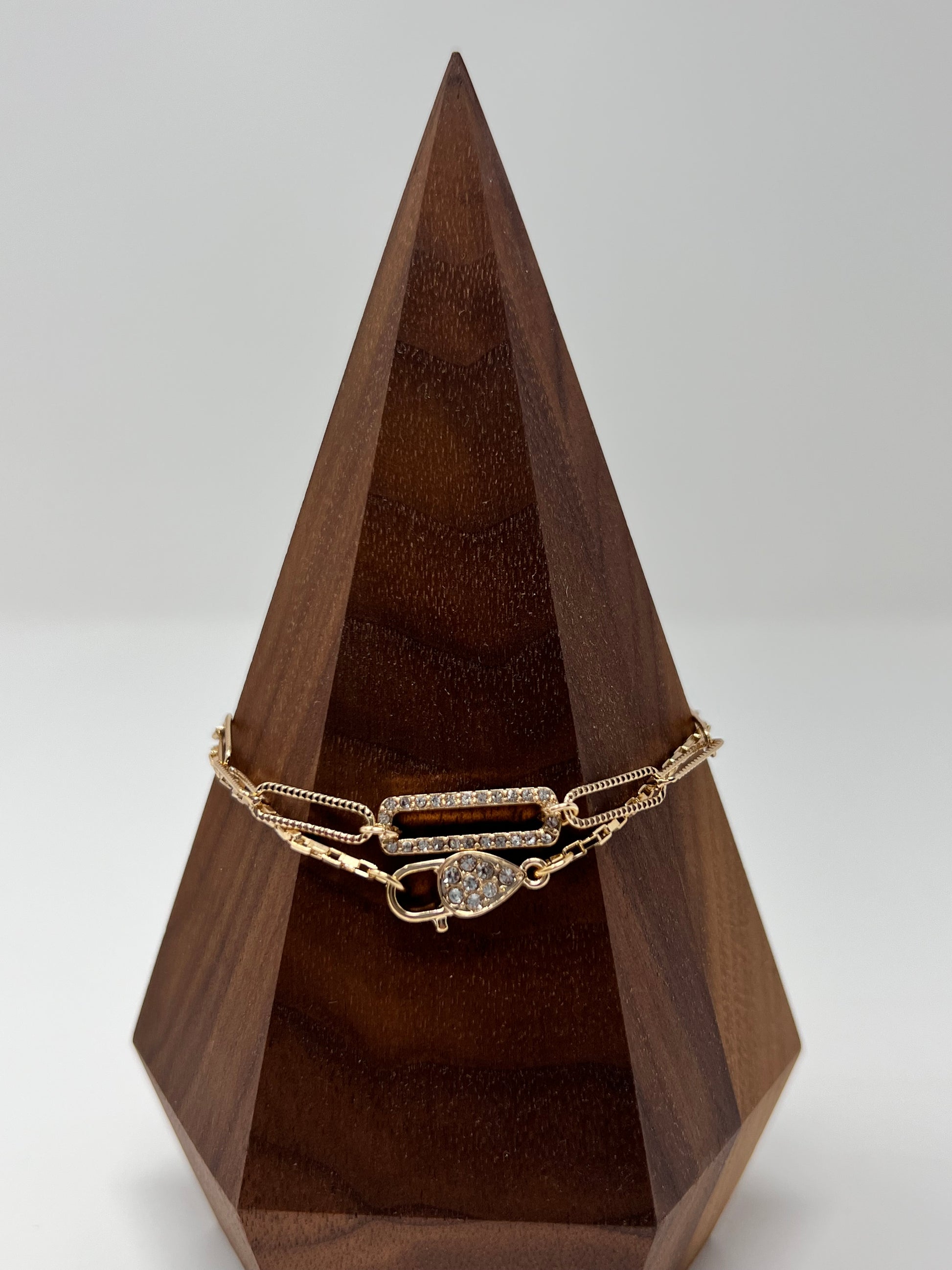 This bracelet is gold tone and is two bracelets. One has a crystal lock and box chain and the other is oval (paperclip) links. They are 7" long with a 2" extender. Lobster claw closure. The lock & oval links measure approximately .75". 