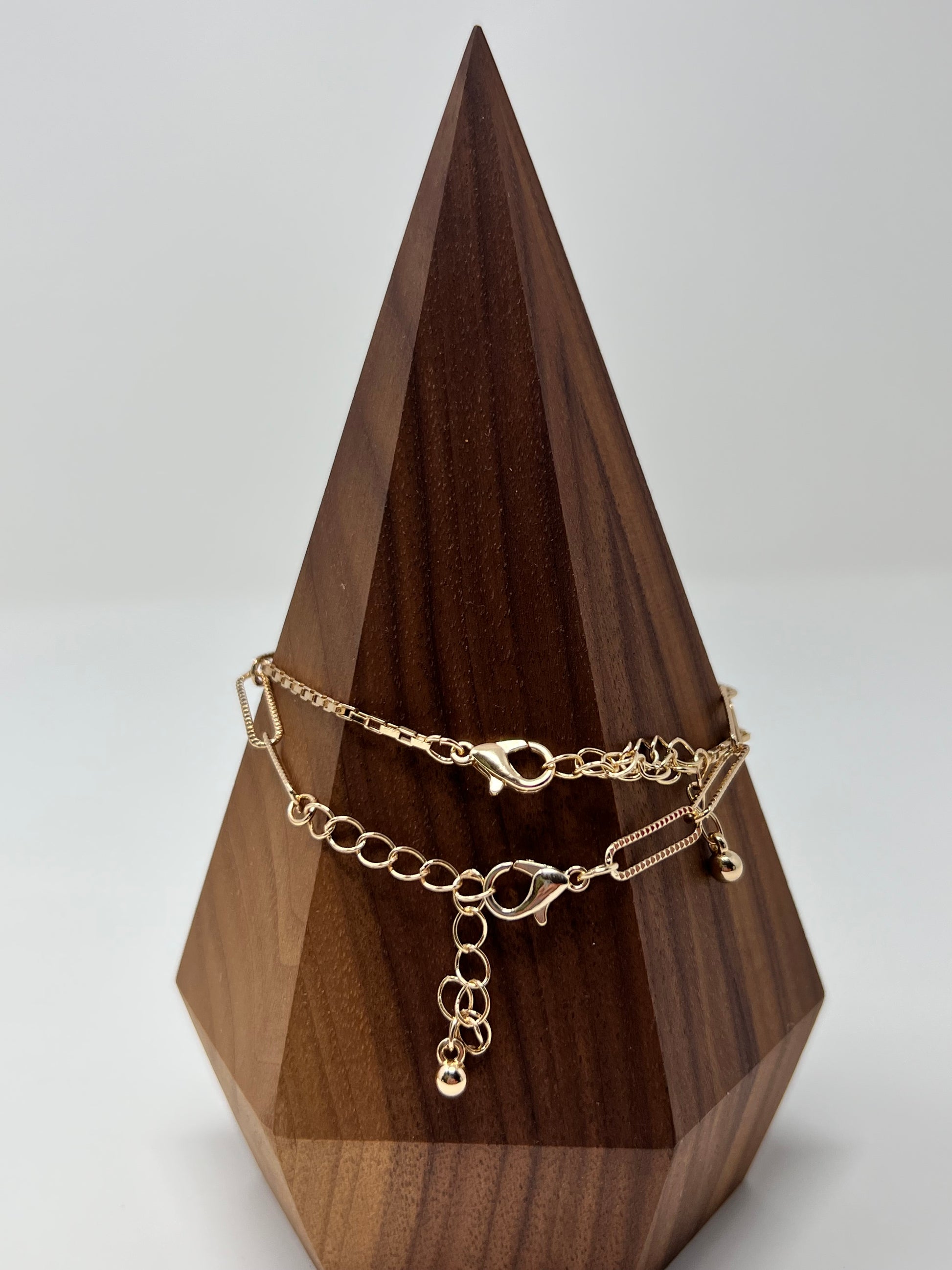 This bracelet is gold tone and is two bracelets. One has a crystal lock and box chain and the other is oval (paperclip) links. They are 7" long with a 2" extender. Lobster claw closure. The lock & oval links measure approximately .75". 