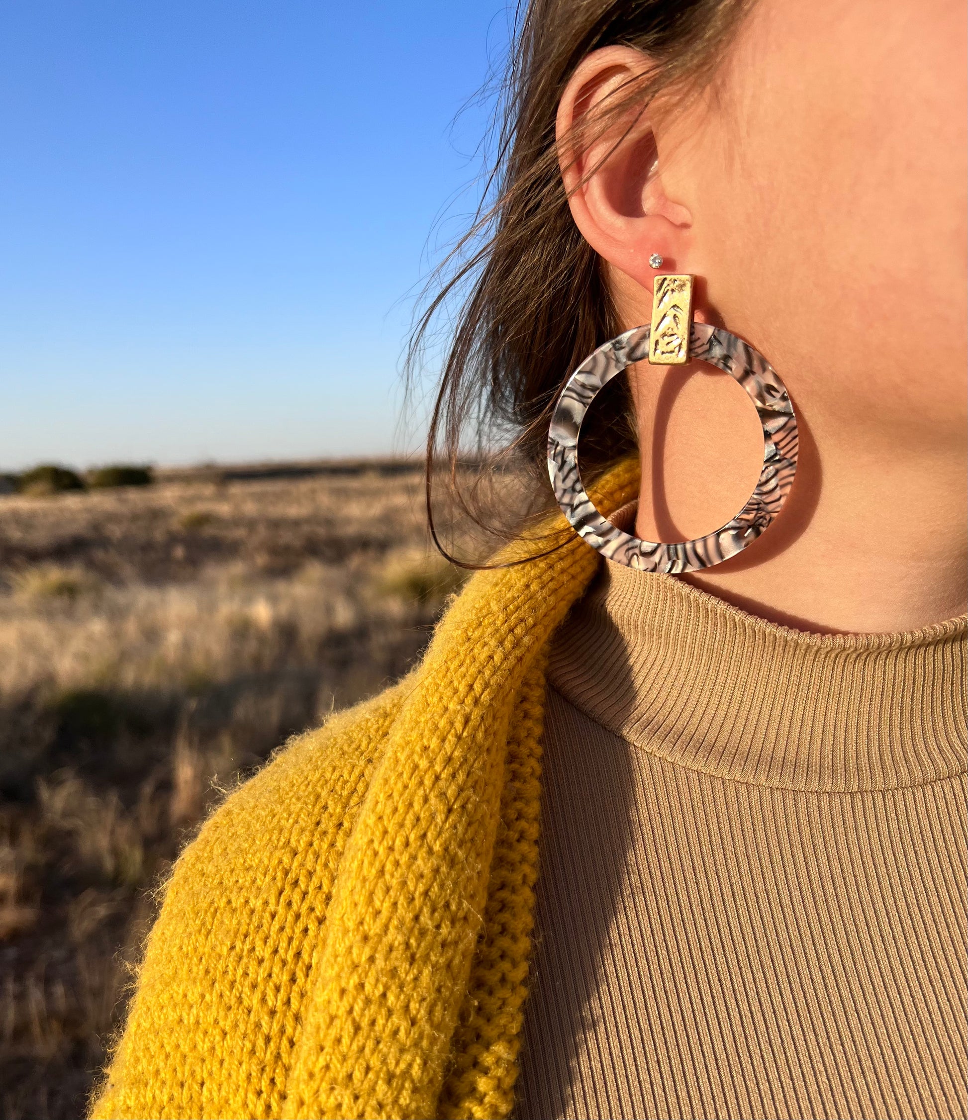 These hoops are a statement piece. They are a gray marbled print resin with a gold tone accent piece at top of earring. They are flat hoops and measure 2.75" and are a post style.