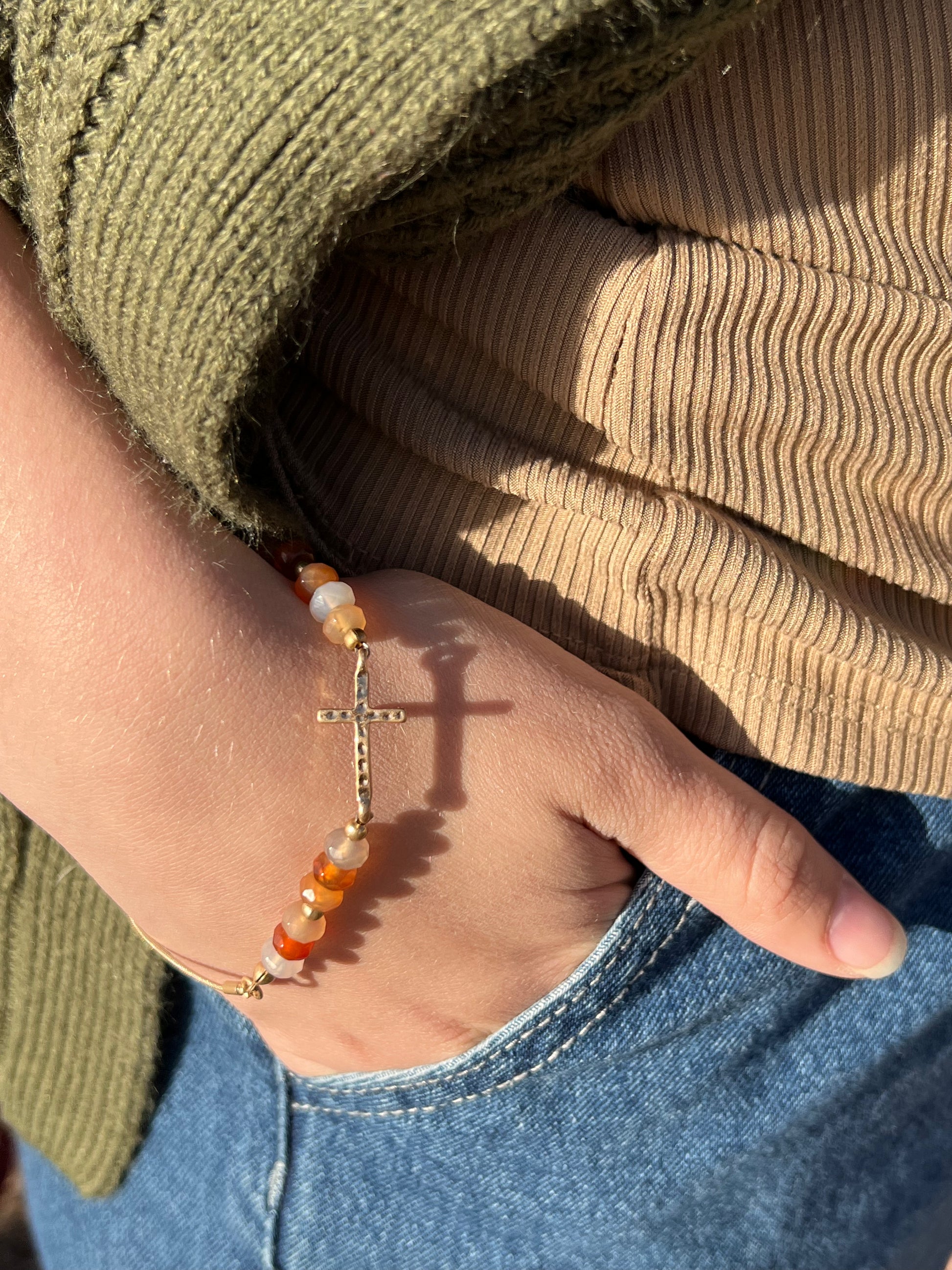 The gold tone cross and peach beads pair so well. It is a unique adjustable pull chain bracelet so there is no clasp closure. 